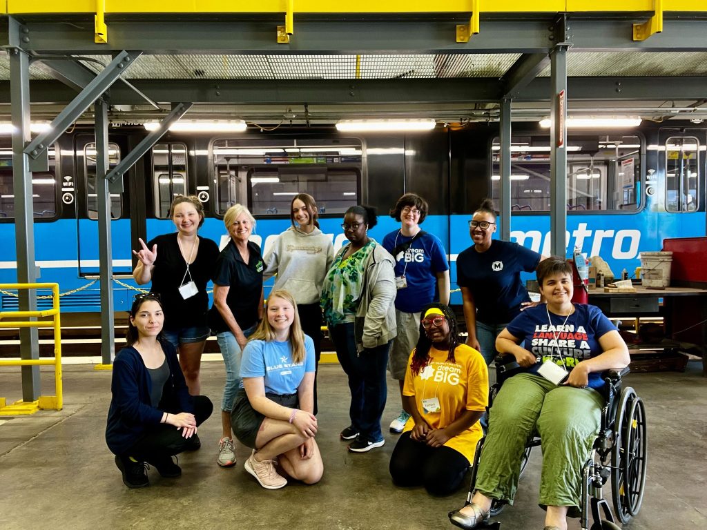 Dream Big campers and staff from Starkloff Disability Institute posing outside a MetroLink train
